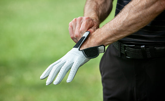 a man putting on his golf glove before his swing