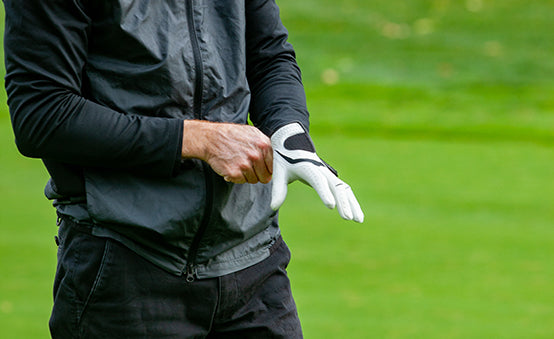A man putting on his golf glove